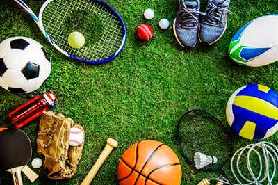 racchetta da tennis, scarpe da ginnastica, palla da calcio, palla da basket, racchette da pin pong ed altri attrezzi sportivi posti su un'area verde